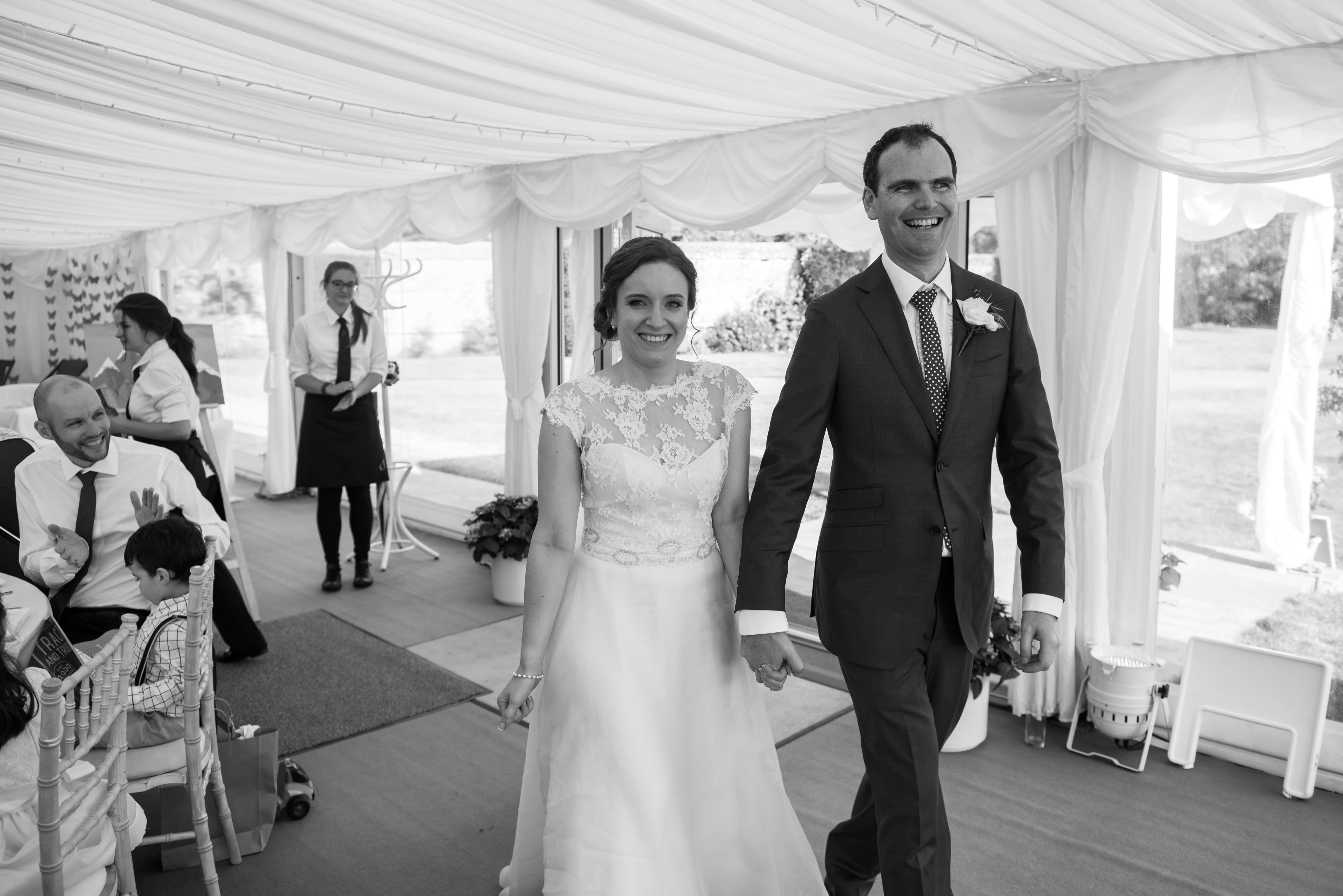 A newly married couple walking in the marquee at Kingston Bagpuize in Oxford